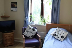 Llwyn Teg Care Home - Bedroom with TV and armchair