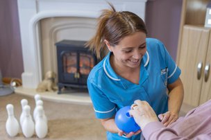 Oak Springs Care Home carer with resident playing bowling game