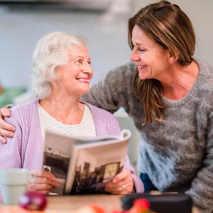 Home Instead Eastbourne and Hailsham carer reading with client