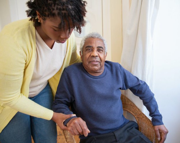 2White Services. Carer helping man out of the chair. 