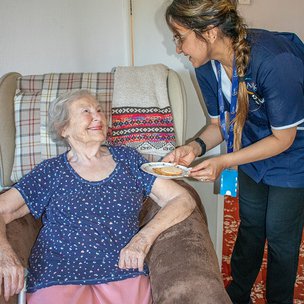 Apollo Care South Wirral - Carer Giving a Snack to Client Who is Smiling at Her