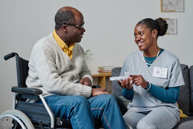 Avida, carer helping man in wheelchair. 