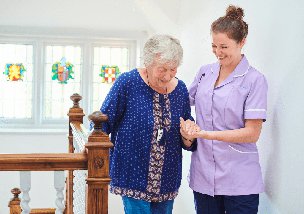 Collens Healthcare live in carer helpinh client up the stairs