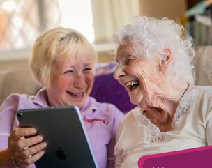 Guardian Angel Carers Reading lady supporting client with ipad