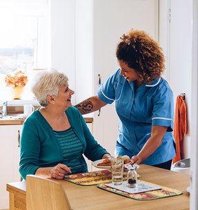 Primacy Homecare Ltd carer helping eldering with lunch