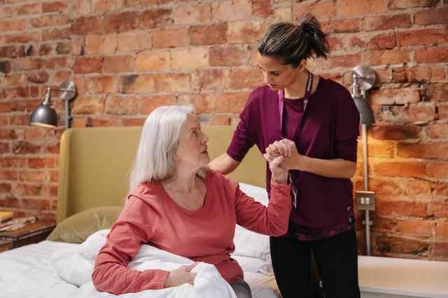 Home Instead Romford. Carer helping lady out of bed 