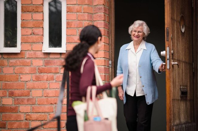 Home Instead Romford. Elderly lady greeting carer at the door. 