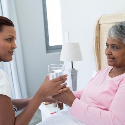 Honeydew Healthcare, carer giving elderly lady a drink 