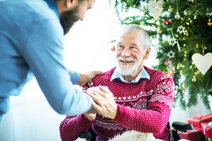 New Age Care Solutions, Merseyside. Carer holding hands with elderly man at Christmas. 