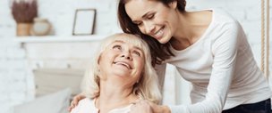 Novus Care, Cranleigh carer smiling over elderly women's shoulder 
