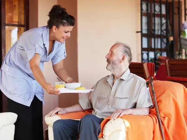 Paddle Healthcare, Dunstable. Carer giving elderly man food. 