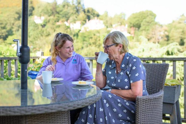 Radfield Home Care Bath, Keynsham & Radstock. Lady drinking tea with eldery lady outside 