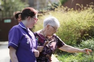 Pilgrims View, Snodland. Carer looking at the flowers with elderly lady. 