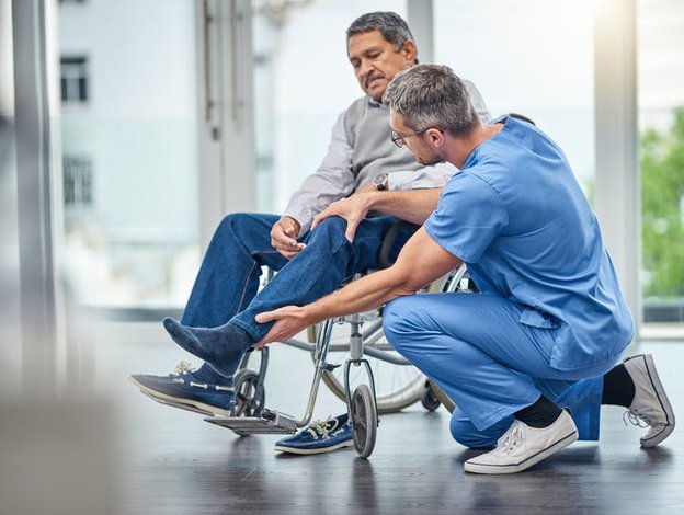 Realcare Health Service. Man in wheelchair with male carer helping him 