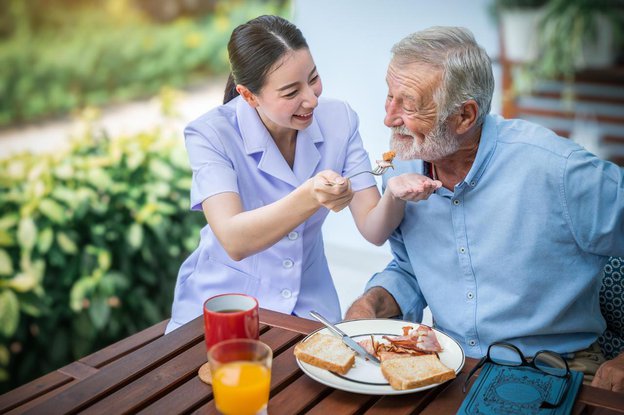 Resume Healthcare, Sheffield. Carer helping elderly man eat 