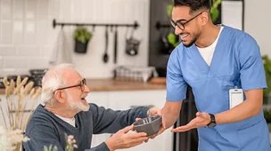 St Annes Nursing Home. Carer giving something to eldery man. 