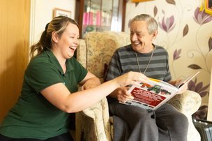 SureCare Central Cheshire, lady talking to elderly man in chair. 