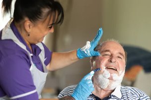 SureCare Cheshire Live in. Carer helping to shave. 