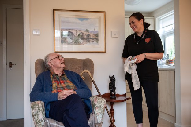 Sylvian care Farnham - carer speaking to elderly man in chair 